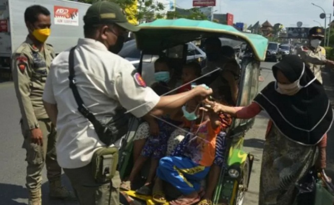 Anggota Satpol PP membagikan masker kepada warga saat operasi penegakan disiplin protokol kesehatan di Kabupaten Gowa