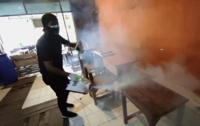 Anggota Komunitas Masyarakat Hijrah Tanpa Nama Ichsan, menyemprotkan uap disinfektan di salah satu Warung Kopi Enreco, Makassar, Sulawesi Selatan